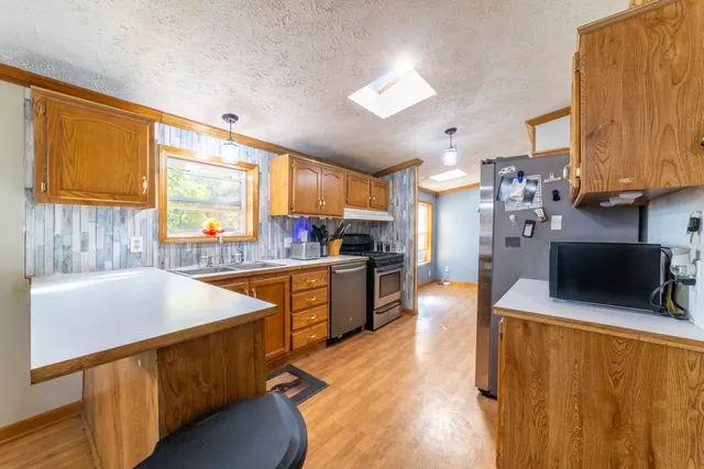 a kitchen with stainless steel appliances kitchen island granite countertop a sink refrigerator and cabinets