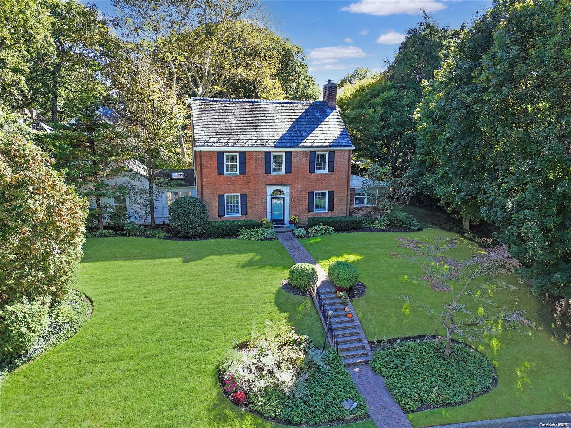 a view of a house with a big yard potted plants and large tree