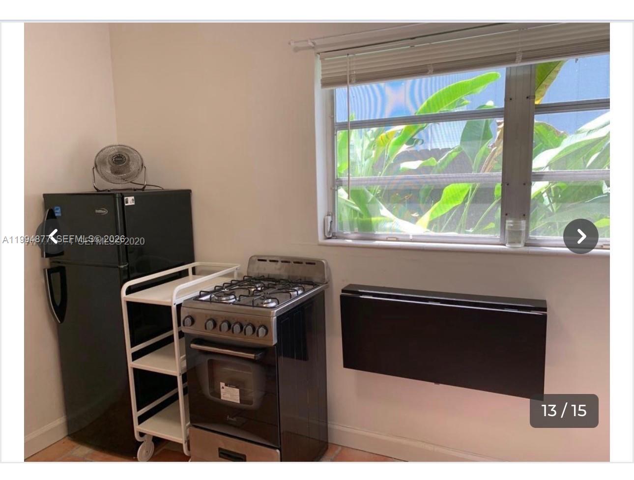 4230 Southwest 11th Street Miami, FL 33134 - Photo 7 of 8 a kitchen with a stove a microwave and a window