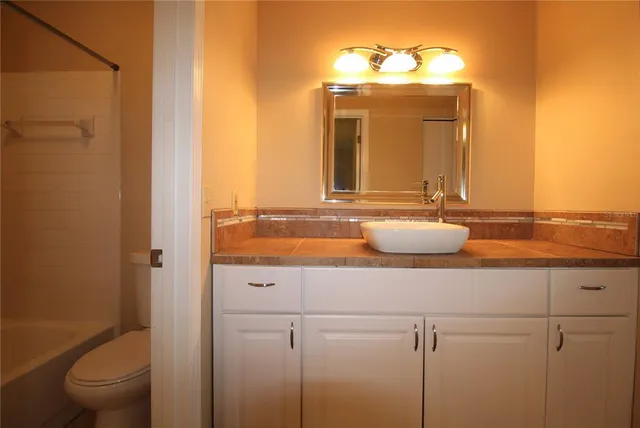 a bathroom with a granite countertop sink a toilet and a mirror