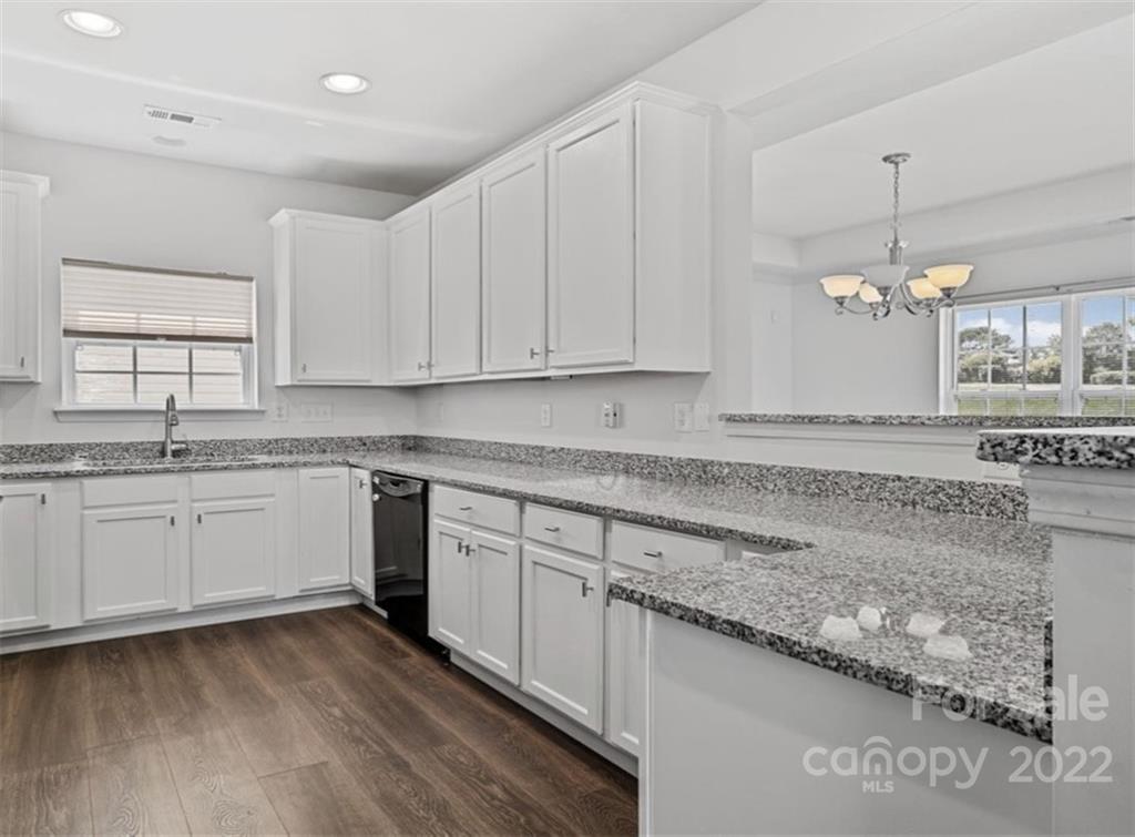 a kitchen with granite countertop a sink cabinets and wooden floor