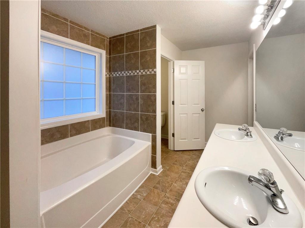 5945 Raventree Court Atlanta, GA 30349 - Photo 24 of 27 a bathroom with a tub and a sink