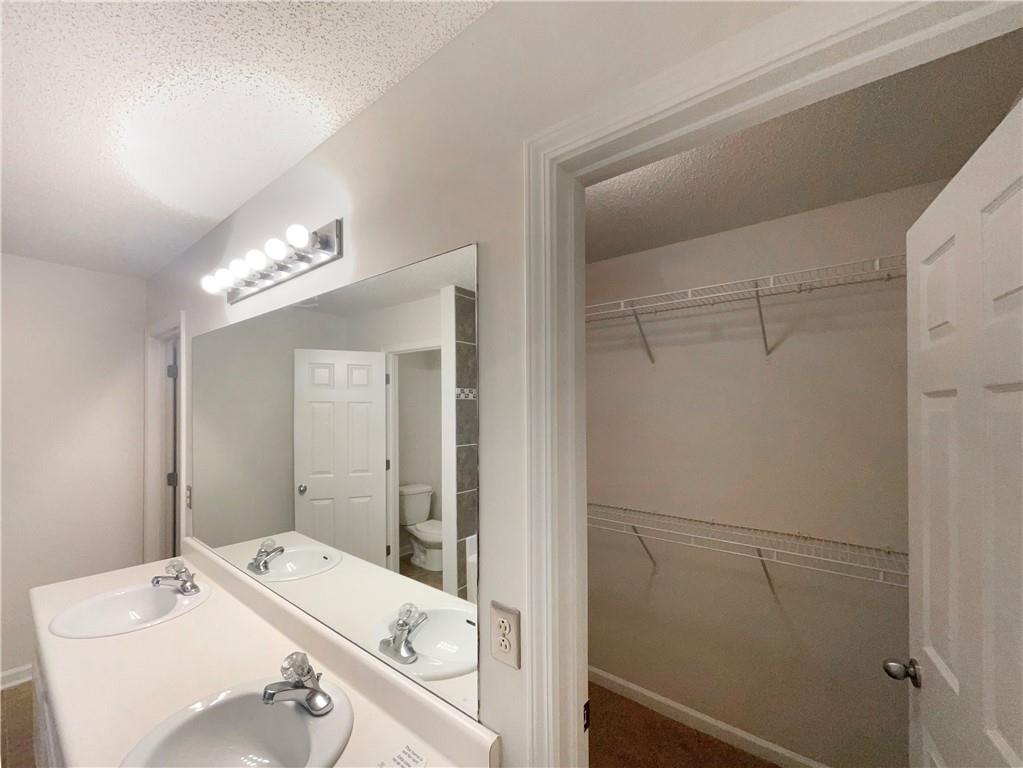 5945 Raventree Court Atlanta, GA 30349 - Photo 7 of 27 a bathroom with a sink a large mirror and a shower