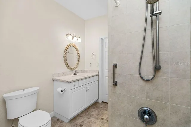 a bathroom with a granite countertop toilet a sink and mirror