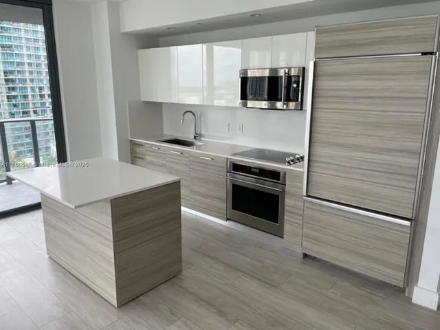 a view of an empty room with wooden floor and windows