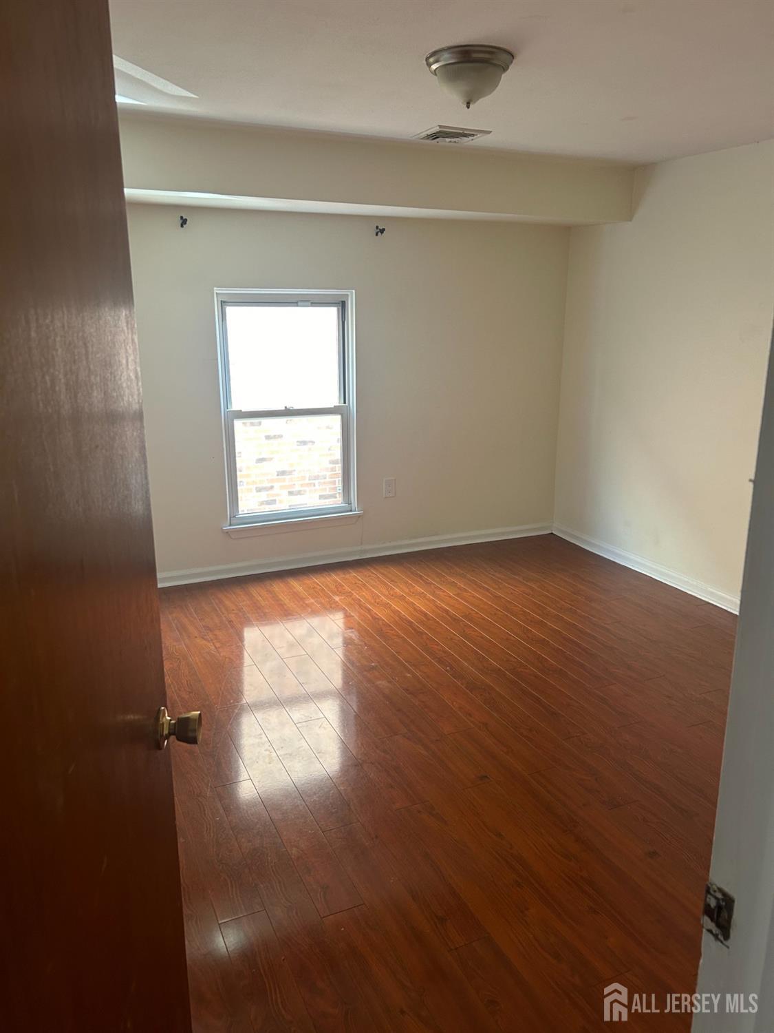 435 Main Street, Unit 2D Metuchen, NJ 08840 - Photo 5 of 8 an empty room with wooden floor and windows