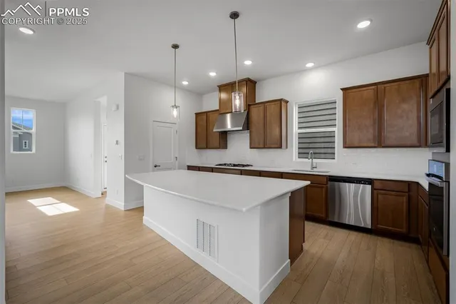 a large kitchen with stainless steel appliances kitchen island a large counter top and wooden floors