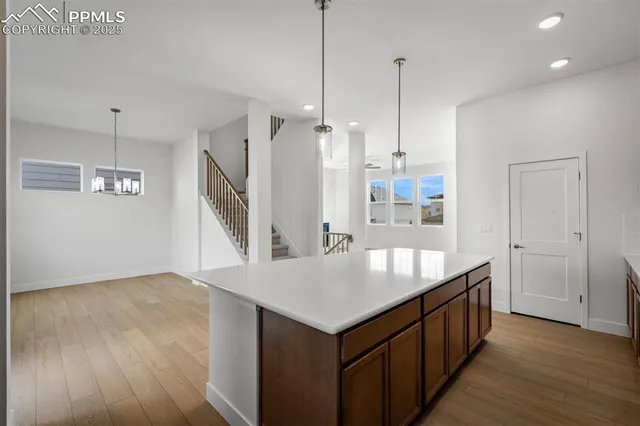 a living room with kitchen island a wooden floor and a ceiling fan