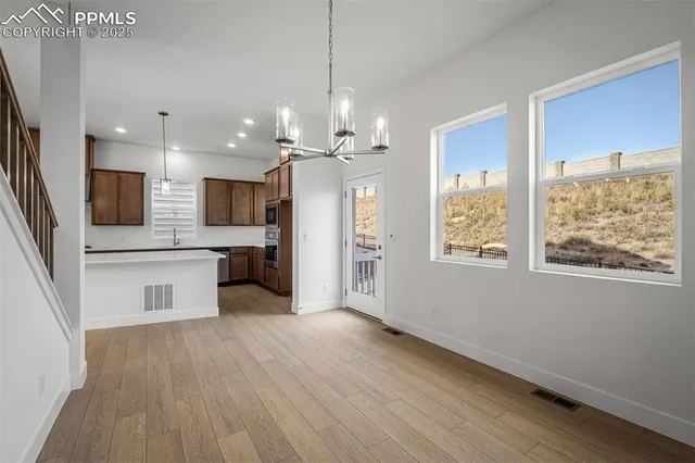 a kitchen with stainless steel appliances a stove top oven a sink dishwasher a refrigerator and white cabinets with wooden floor