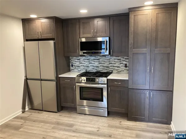 a metallic refrigerator freezer and a stove sitting inside of a kitchen
