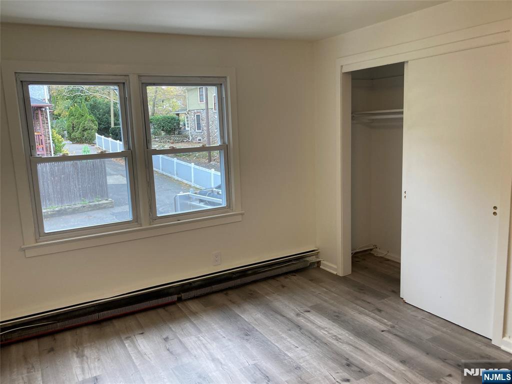 118 Doremus Avenue, Unit C Ridgewood, NJ 07450 - Photo 10 of 16 an empty room with wooden floor and windows