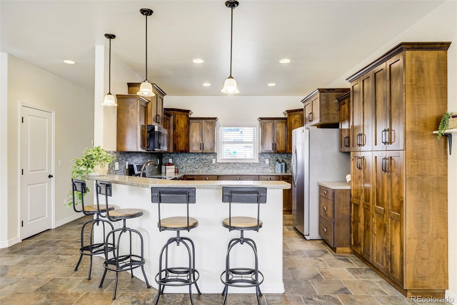 675 9th Street Limon, CO 80828 - Photo 22 of 49 a kitchen with stainless steel appliances kitchen island granite countertop a refrigerator a stove a kitchen island with chairs and white cabinets