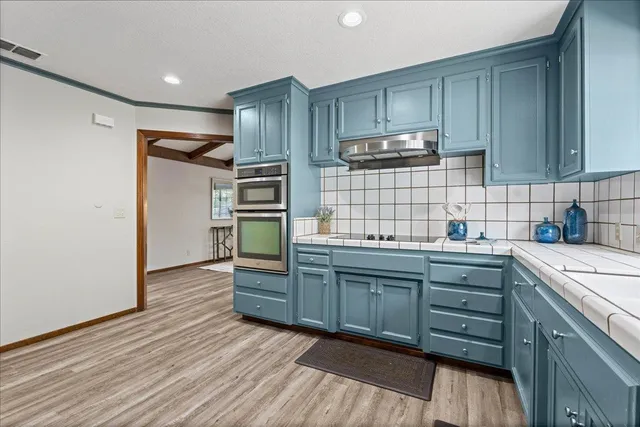a kitchen with stainless steel appliances kitchen island granite countertop a refrigerator and a stove top oven
