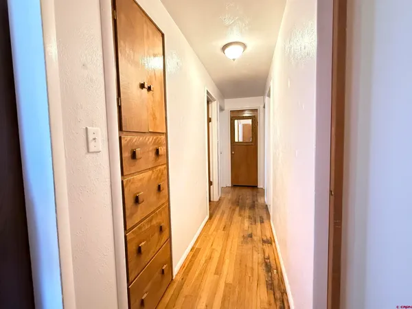 a view of a hallway with wooden floor and a bathroom
