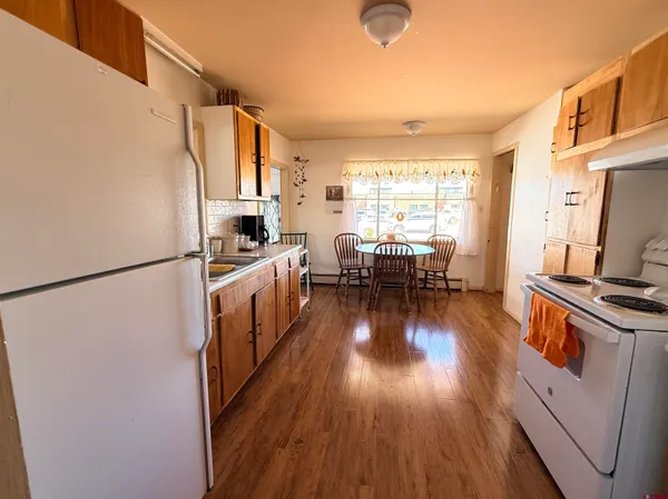 a kitchen with stainless steel appliances a refrigerator a stove a sink dishwasher a oven with wooden floor and cabinets