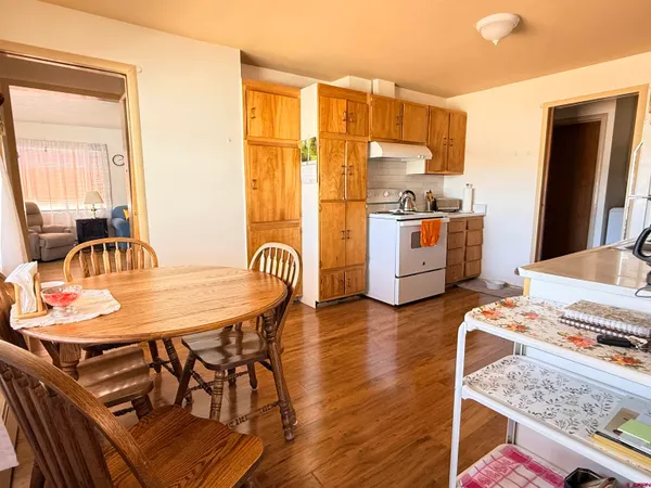 a open kitchen with stainless steel appliances granite countertop a stove top oven a sink a dining table and chairs with wooden floor