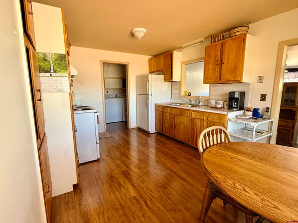 a kitchen with stainless steel appliances a dining table chairs sink and wooden floor