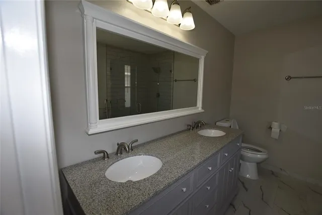 a bathroom with a granite countertop sink toilet and mirror