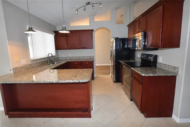 a kitchen with granite countertop a sink a stove and cabinets