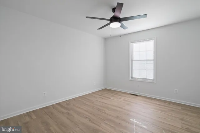 an empty room with a window and a fan
