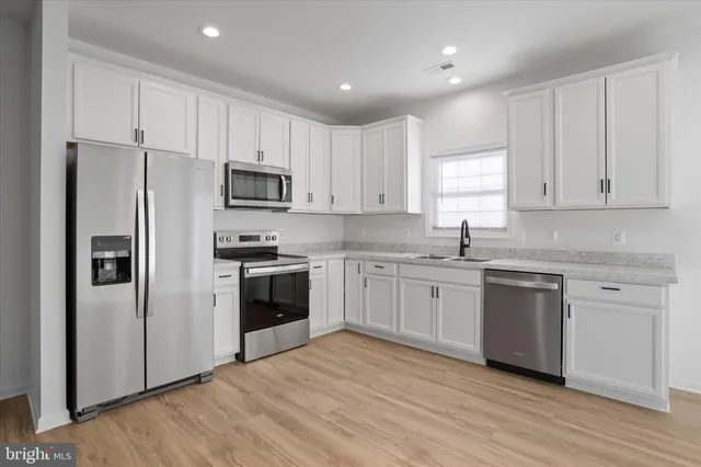 a kitchen with granite countertop white cabinets and stainless steel appliances