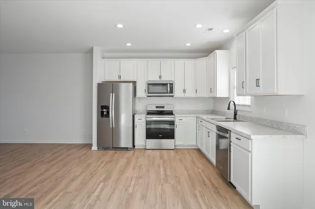 a kitchen with granite countertop a refrigerator stove top oven and wooden floor