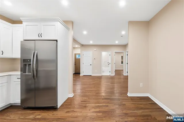 a view of a kitchen with a refrigerator and wooden floor