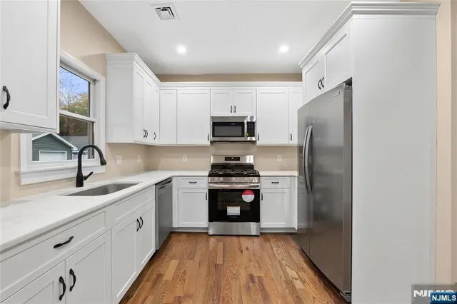 a kitchen with stainless steel appliances granite countertop a stove a sink and a refrigerator