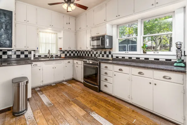 a kitchen with granite countertop a stove a sink and white cabinets