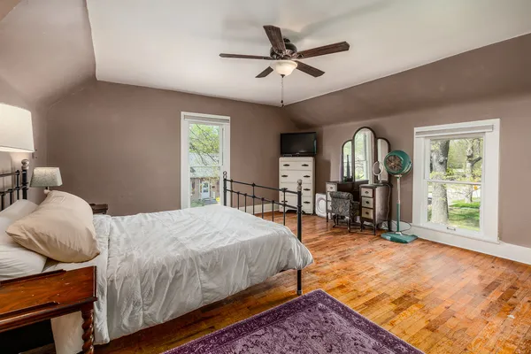 a spacious bedroom with a bed a dresser and windows