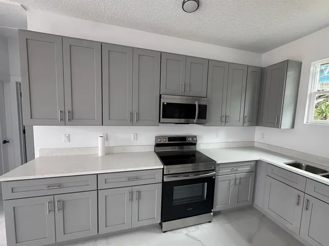 a kitchen with white cabinets and appliances