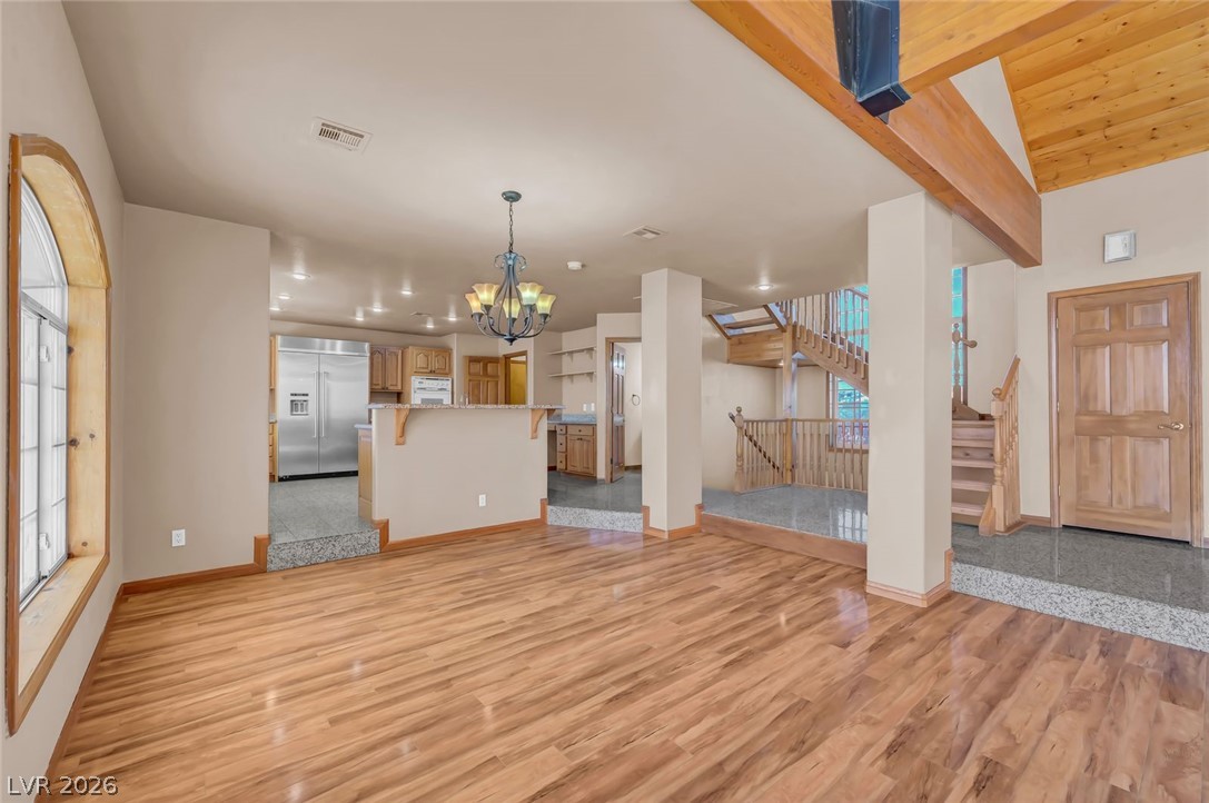 640 North Racetrack Road Henderson, NV 89015 - Photo 21 of 65 Natural wood tones grace this open-concept space, linking the kitchen, living area, and a striking staircase.
