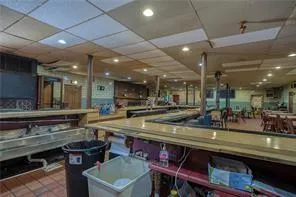 a dining hall with stainless steel appliances granite countertop a table chairs and a sink