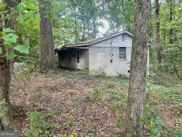 a backyard of a house with large trees and plants