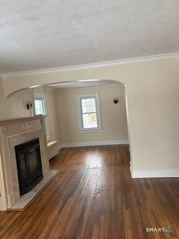 a view of an empty room with wooden floor fireplace and a window