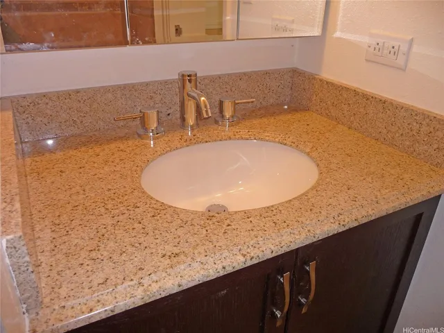 a bathroom with a granite countertop sink and mirror