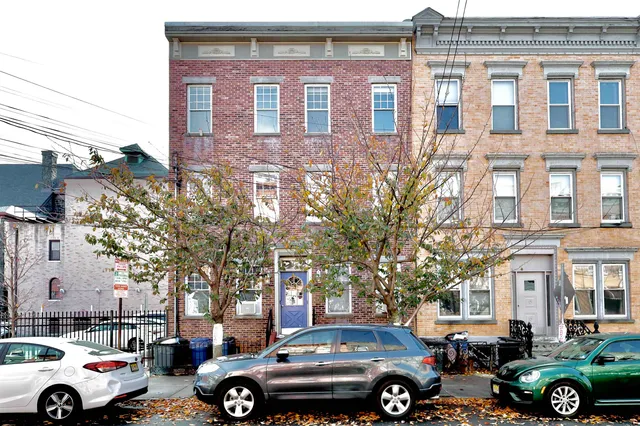 a front view of a building with parking space and a car parked in front of it