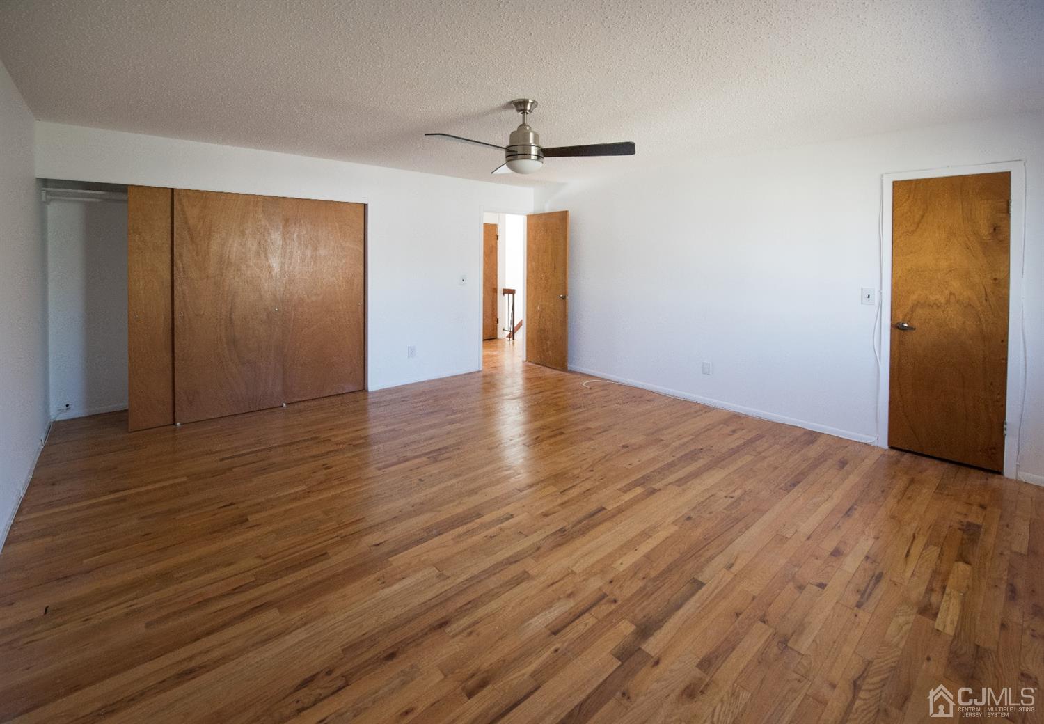 5403 Hana Road Edison, NJ 08817 - Photo 7 of 12 a view of an empty room with wooden floor and a ceiling fan
