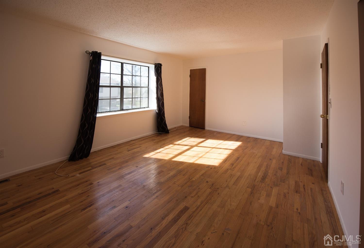 5403 Hana Road Edison, NJ 08817 - Photo 10 of 12 an empty room with wooden floor and windows