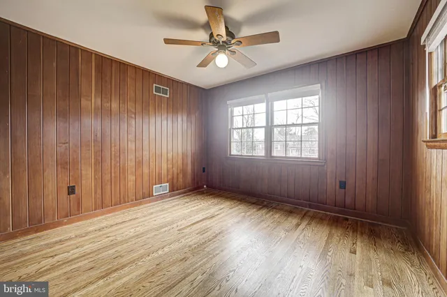 an empty room with wooden floor closet and windows
