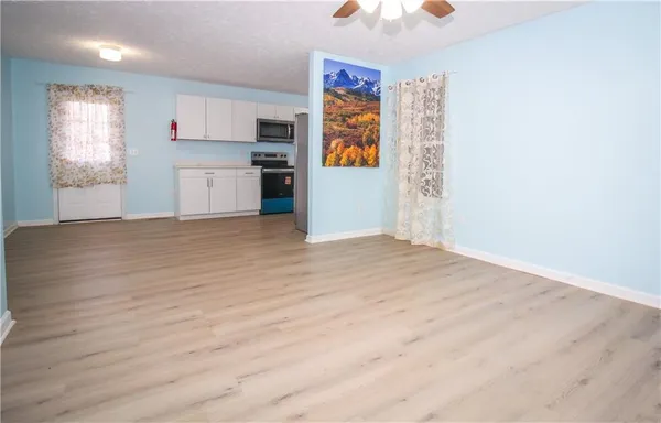 a view of a kitchen with wooden floor electronic appliances and window