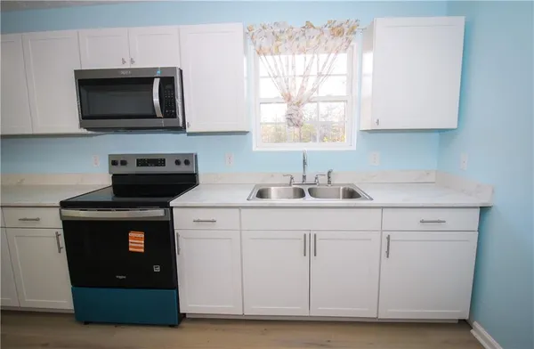 a kitchen with stainless steel appliances granite countertop a sink a microwave a stove and cabinets