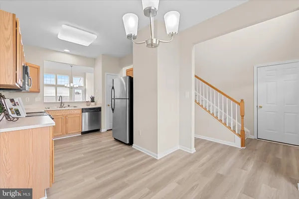 a kitchen with a refrigerator a sink and dishwasher with wooden floor
