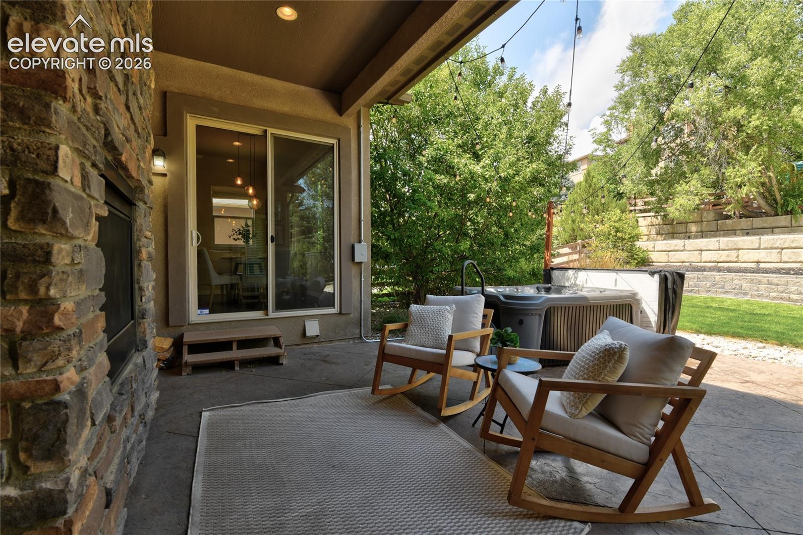1118 Spectrum Loop Colorado Springs, CO 80921 - Photo 37 of 50 Patio featuring a stone-clad fireplace, sliding glass door, string lighting, and an integrated hot tub