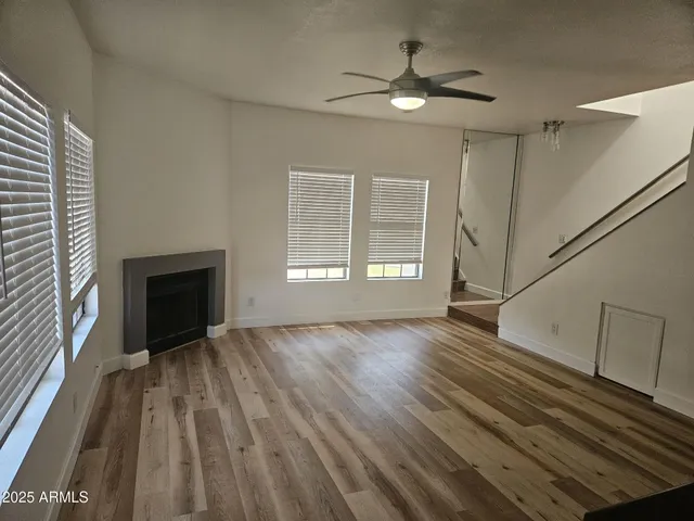 a view of an empty room with wooden floor fireplace and a window