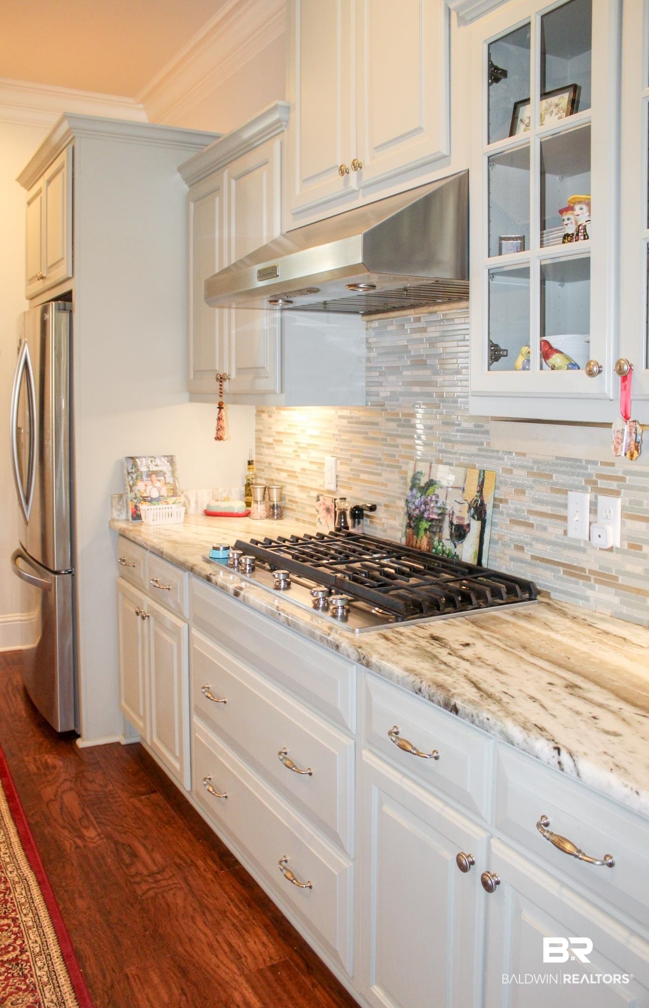 375 Barndling Street Fairhope, AL 36532 - Photo 9 of 24 Kitchen with light stone countertops, appliances with stainless steel finishes, dark hardwood / wood-style flooring, tasteful backsplash, and white cabinetry