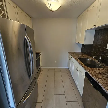 a kitchen with a sink a refrigerator and cabinets
