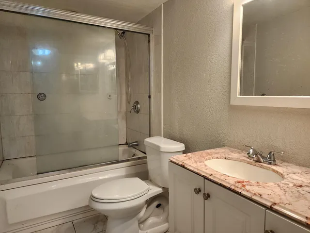 a bathroom with a granite countertop sink toilet and shower