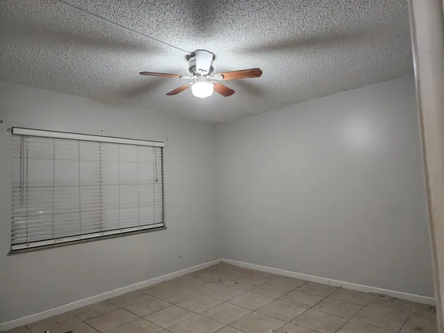 an empty room with windows and fan