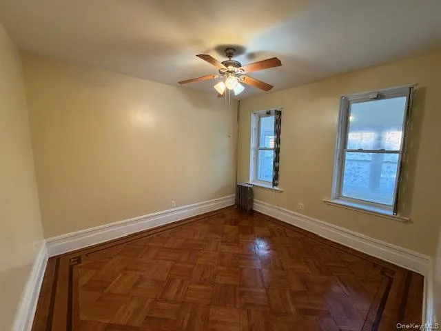 a view of an empty room with window and chandelier fan